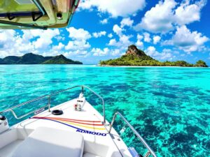 A boat navigating through turquoise waters near tropical islands.